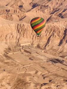 a hot air balloon flying over an ancientramids in the desert at Rose travel_trips in Jazīrat al ‘Awwāmīyah