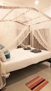 Una cama con mosquitera encima. en Tropical Inn, en Mirissa
