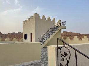 a building with a staircase on the side of it at Castello Bianco in Shabīkah