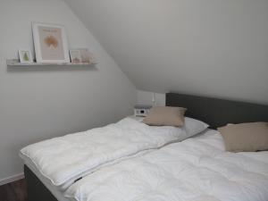 ein weißes Bett mit zwei Kissen darüber in der Unterkunft Nordseehus-HYGGE in Butjadingen