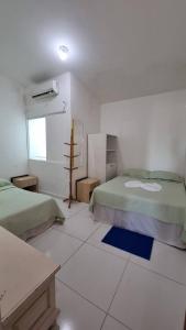 Cette chambre blanche dispose de deux lits et d'une fenêtre. dans l'établissement Appartement Belle Paris - Beira Mar Praia do Francês, à Marechal Deodoro