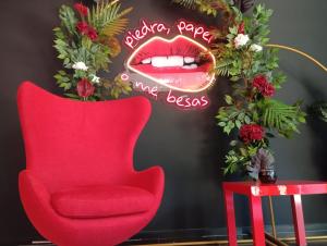 Una silla roja y una señal que dice besos de labios de Servina en Hotel Playa Ribera en Suances