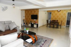 バンガロールにあるUrban Stay Adams Service Apartmentのリビングルーム(ソファ、テーブル付)