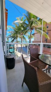 d'un balcon avec des chaises, une table et des palmiers. dans l'établissement Appartement Belle Paris - Beira Mar Praia do Francês, à Marechal Deodoro