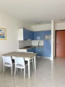 una cocina con armarios azules y una mesa y sillas de madera. en Residence la Duna 5D, en Lignano Sabbiadoro