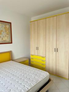1 dormitorio con 1 cama y armario amarillo en Residence la Duna 5D, en Lignano Sabbiadoro