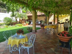 patio ze stołami i krzesłami pod pergolą w obiekcie Villa Olga B&B w mieście Formia