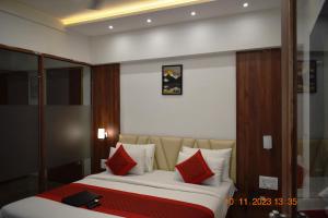 1 dormitorio con 1 cama con almohadas rojas y blancas en LEELA BIZOTEL en Jūnāgadh