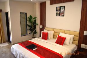 a bedroom with a large bed with red pillows at LEELA BIZOTEL in Junagadh