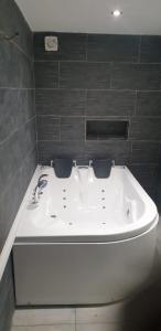 a white bath tub in a bathroom with black tiles at Maison chaleureuse in Casseneuil