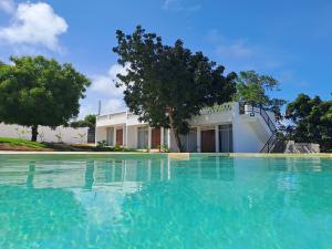 a pool of water in front of a house at Cave Diani Holiday Apartments in Diani Beach