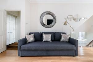 a blue couch in a living room with a mirror at Beautiful 4 Bedroom House near Paddington Station in London