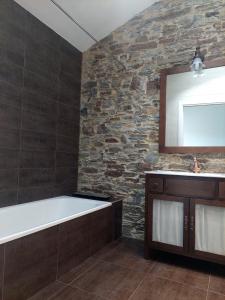 uma casa de banho com uma banheira e uma parede de pedra em SAN FRANCISCO em Ribadeo