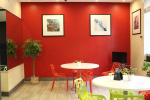 una pared roja en una sala de espera con mesas y sillas en Club Hotel, en Milán