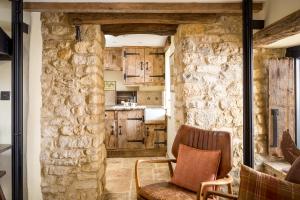 - une cuisine avec des placards en bois et une chaise dans la chambre dans l'établissement Bantam Tea Rooms, à Chipping Campden