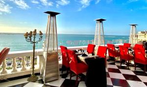 un ristorante con sedie rosse e vista sull'oceano di Le Metropole Luxury Heritage Hotel Since 1902 by Paradise Inn Group ad Alessandria d'Egitto