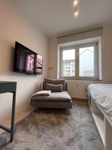 a bedroom with a chair and a tv on the wall at Quiet and sunny studio in Ddorf absolut city center in Düsseldorf