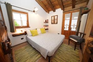 ein Schlafzimmer mit einem Bett mit gelben Kissen und einem Stuhl in der Unterkunft RUSTICO VIGNA casa vacanze in Civo