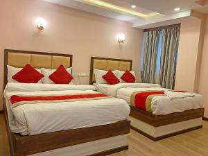 two beds in a hotel room with red pillows at Hotel White Rabbit in Kathmandu