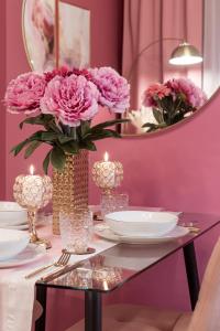 un tavolo con un vaso di fiori rosa e candele di Designer Luxury Apartment near Prater a Vienna