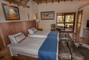 a bedroom with two beds and a couch at Ilanga Safari Lodge - Welgevonden Game Reserve in Vaalwater