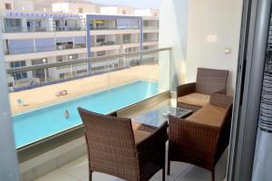 a balcony with a table and chairs and a swimming pool at Apartment am Meer mit Pool in Aourir