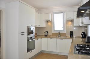 a white kitchen with white cabinets and a window at Villa Steve in Fethiye