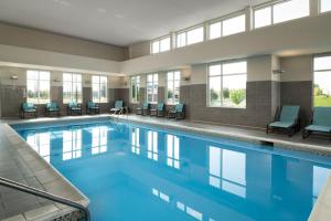 uma piscina num hotel com cadeiras e janelas em Residence Inn by Marriott Green Bay Downtown em Green Bay