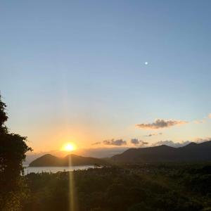a sunset over a city with the sun in the sky at Pousada Villa Blu Maresias in Maresias