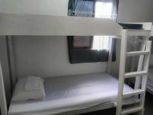 a white bunk bed with a ladder and a window at Alegreya Homestay + Cafe in General Luna