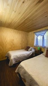 a bedroom with two beds and a wooden ceiling at Sector 3 de Camping Angostura in Lago Rapel