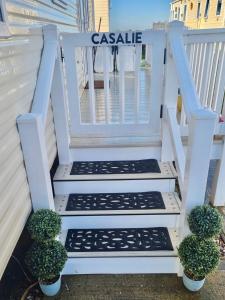 eine weiße Treppe, die zu einem Haus mit Topfpflanzen führt in der Unterkunft CASALIE at Seasalter Whitstable in Seasalter