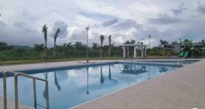a large swimming pool with palm trees in the background at Spacious Luxury Condo w/ kitchen beside Hilton Clark D’Heights in Pampang