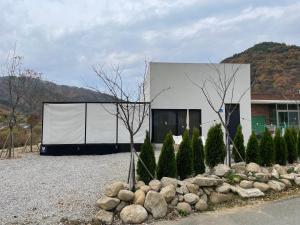 a white building with trees and rocks in front of it at Stay Timoga - Private Poolvilla in Muju