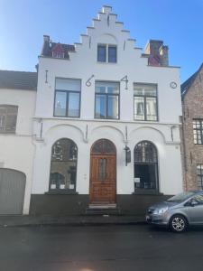 布鲁日Guesthouse 1640的街上有一道白色的建筑,有一道棕色的门