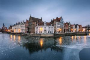 a city with buildings and a river at night at Guesthouse 1640 in Bruges