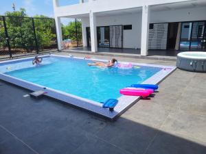 two people playing in a swimming pool with a pool toy at Villa Sylla fall in Toubab Dialaw