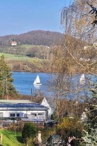 um barco num lago com uma casa e um veleiro em Vierzimmerwohnung am Harkortsee em Wetter