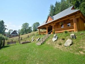a wooden cabin on a hill with rocks in the grass at Pokoje Gościnne Bożena Dunajczan in Brzegi