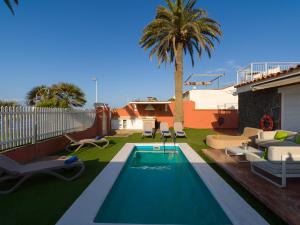 a swimming pool with chairs and a palm tree at El Veril by CanariasGetaway in San Agustin