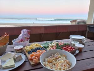 a table with plates of food on a table with the beach at At home on the beach... in Jeffreys Bay
