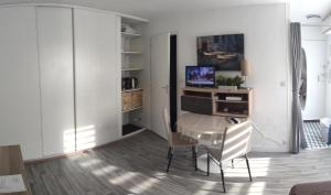 uma sala de estar com uma mesa e cadeiras e uma televisão em STUDIO CALME PROCHE CENTRE BORDEAUX em Bordeaux