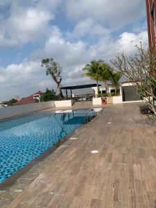 a swimming pool with a wooden floor and palm trees at Barsa city by oye luxury in Yogyakarta