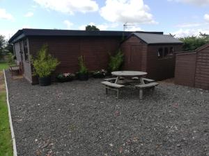 a picnic table and bench in a gravel yard at Log cabin with secure garden in Haxey
