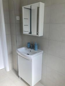 a white bathroom with a sink and a mirror at Madách lakás in Győr