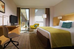 Habitación de hotel con cama, escritorio y TV. en Courtyard by Marriott Montpellier, en Montpellier