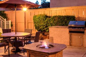 uma fogueira num pátio com uma mesa e comodidades para churrascos em Residence Inn San Jose Campbell em Campbell