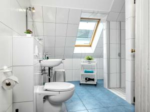 a white bathroom with a toilet and a sink at Haus Maja in Kaltenhof