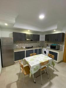 a kitchen with a table with chairs and a refrigerator at Mina résidence A4 in Kelibia