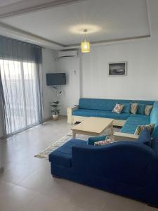 a living room with a blue couch and a table at Duplex El Mansoura A4 in Kelibia